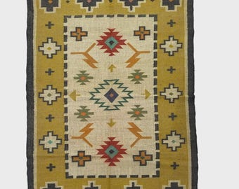 May include: A rectangular rug with a mustard yellow border and a cream-colored center. The rug features geometric patterns in red, blue, green, and orange. The border is dark gray, and the rug has fringe on the short ends. The rug is suitable for a living room or bedroom.