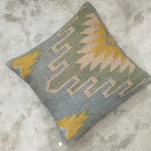 Könnte beinhalten: Quadratisches Zierkissen mit einem geometrischen Muster in Blau-, Grün-, Beige- und Gelbtönen. Das Kissen hat ein strukturiertes Aussehen, wobei das Design eckige Formen und Linien aufweist. Das Kissen ist wahrscheinlich aus gewebtem Stoff.