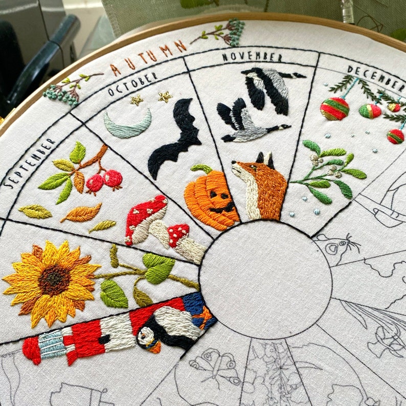May include: Embroidered hoop art depicting the months of the year with seasonal imagery. September features a sunflower, October has a bat and a pumpkin, November has geese, December has a Christmas tree, and January has a puffin.
