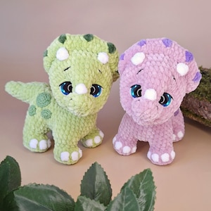 May include: Two handmade plush triceratops dinosaurs. One is light green with dark green spots, the other is lavender with purple spots. Both have white accents and large blue eyes. Suitable for children.
