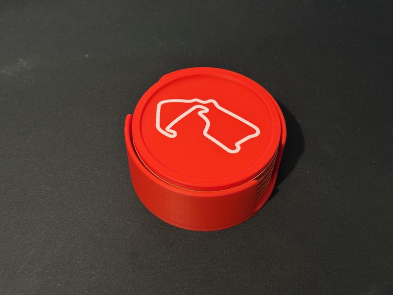 Puede incluir: Un juego de posavasos rojos con un contorno blanco de una pista de carreras. Los posavasos est&aacute;n apilados uno encima del otro.