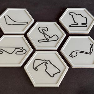 May include: Six hexagonal coasters with a white background and black outlines of different race tracks.