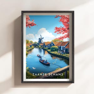 May include: Framed art print of Zaanse Schans, Netherlands. The image depicts a scenic canal with boats, traditional houses, and a windmill under a blue sky with pink flowering trees. The text "ZAANSE SCHANS NETHERLANDS" is at the bottom.