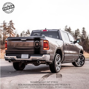 May include: A gray pickup truck with a black and white decal of the Star Wars Imperial symbol on the back. The decal is on a black stripe that runs down the side of the truck.