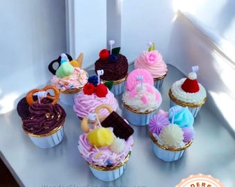 May include: Assortment of 10 colorful cupcakes with various toppings, including chocolate, sprinkles, fruit, and pretzels. The cupcakes are in blue and white paper liners. The cupcakes are arranged on a white surface. The text "WonderGlowCandles.etsy.com" is visible at the bottom of the image.