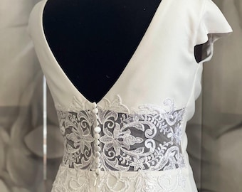 Elegante vestido de novia de crepé con encaje en la espalda y cola. Vestido de novia a medida con escote en V y botones.