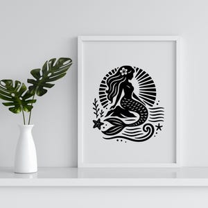 May include: Black and white illustration of a mermaid sitting on a wave with a sunburst behind her. The mermaid has a flower in her hair and a long flowing tail.