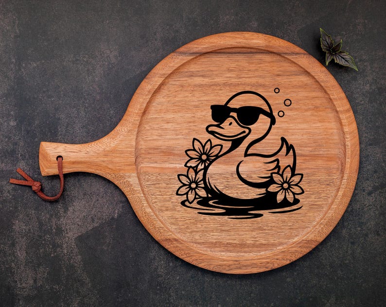 May include: A wooden serving board with a handle, featuring a black and white illustration of a duck wearing sunglasses and surrounded by flowers.