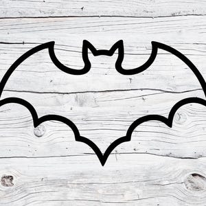 May include: A black outline of a bat silhouette against a white and gray wooden background. The bat has a pointed head and wings spread wide, with a jagged bottom edge. The image is simple and graphic, suitable for Halloween or gothic-themed designs.