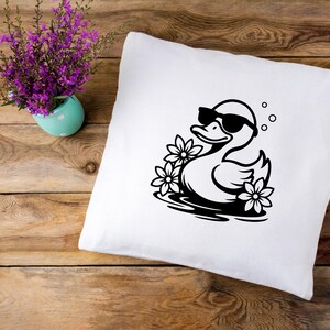 May include: White pillowcase with a black and white illustration of a duck wearing sunglasses and floating in a pool of water with flowers.