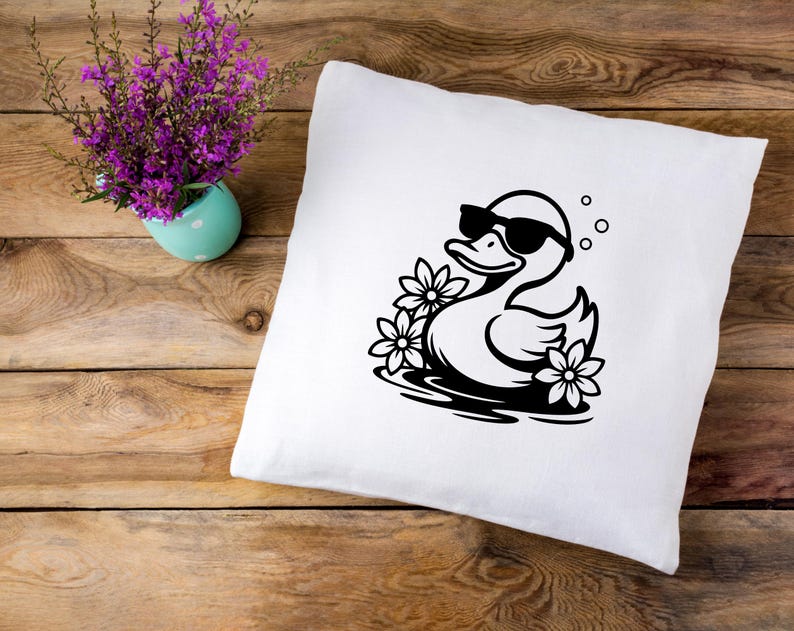 May include: White pillowcase with a black and white illustration of a duck wearing sunglasses and floating in a pool of water with flowers.