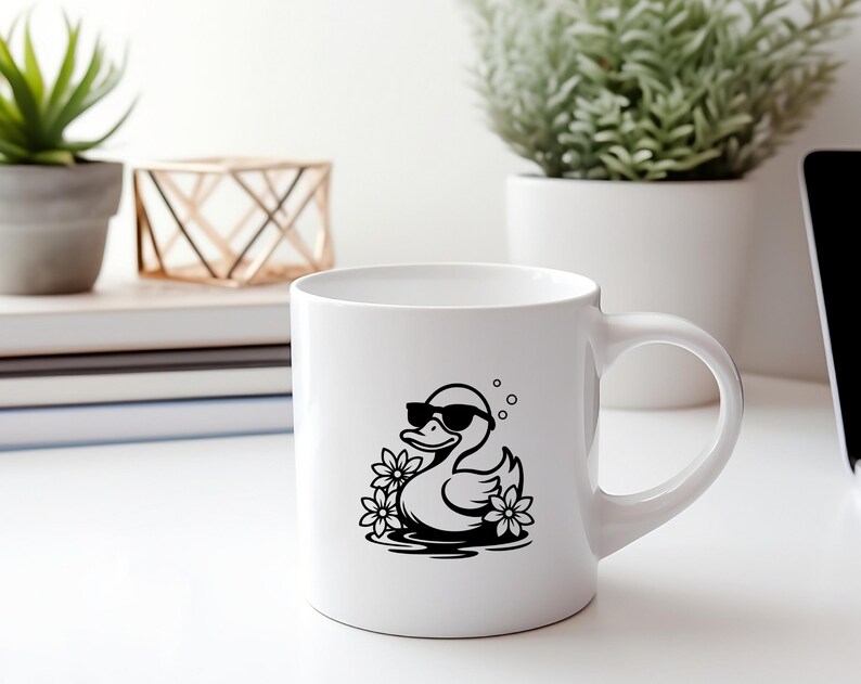 May include: White ceramic mug with a black and white illustration of a duck wearing sunglasses and floating in water with flowers.