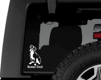 May include: White vinyl decal of a boxer dog sitting with the text "Boxer Dad" on a black car.