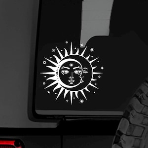 May include: White celestial sun and moon sticker. The sun features a face with a detailed design, surrounded by rays. The moon has a profile of a face. The design includes stars and dots.