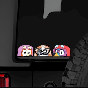 Può includere: Un adesivo con tre personaggi di cani dei cartoni animati con aspetti distinti. I cani sbirciano sopra un bordo, ognuno con copricapo ed espressioni uniche. L'adesivo è probabilmente progettato per la decorazione di veicoli o superfici.