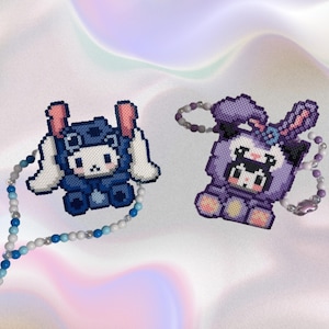 May include: Two beaded necklaces with pixelated animal charms. One necklace has a blue and white charm of a bunny wearing a helmet. The other necklace has a purple charm of a bunny with a bow.
