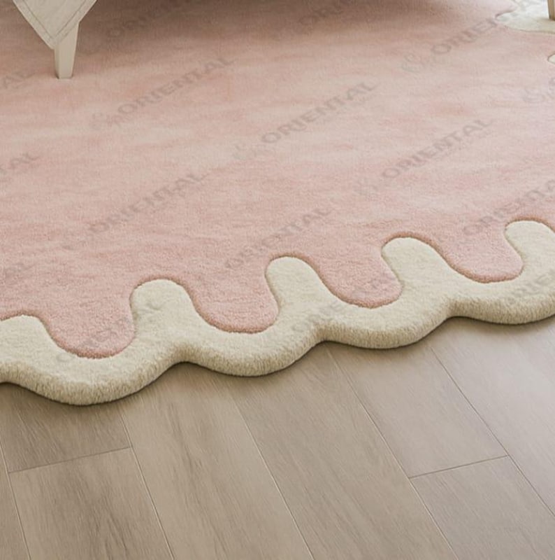 Modern scalloped edge rug 4x6 ft in pastel pink under bed Handmade wool rug 6x9 ft with cream border in bright bedroom.