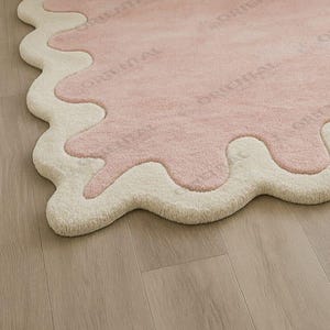 Handmade scallop rug 6x9 ft in light-filled cozy bedroom Hand tufted pink wavy edge rug 5x7 ft styled in cozy white bedroom.