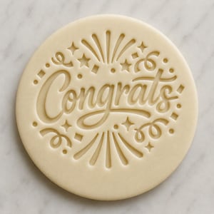 May include: A circular biscuit with the word "Congrats" in a cursive font. The biscuit is decorated with star and firework designs around the text, creating a celebratory theme. The biscuit is a light beige colour.