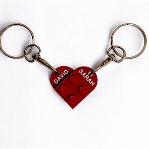May include: A red heart-shaped keychain with the names "DAVID" and "SARAH" on it. The keychain is made of two interlocking key rings.