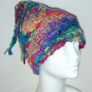 May include: A colourful knitted hat with a long tail, made with a variety of yarns in shades of blue, pink, purple, and green.