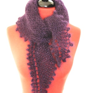 Könnte beinhalten: Ein lila gestrickter Schal mit einem zarten Spitzenmuster an den Rändern. Der Schal ist über eine Schaufensterpuppe gelegt.