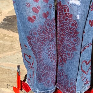 View the light distressing, red mandala stenciling, roses, garlands and the word "love" near the hem line.