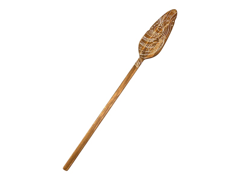 Op de afbeelding: Een houten peddel met een gesneden ontwerp. De peddel is bruin en heeft een wit ontwerp.