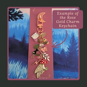 Stag Throne of Glass Inspired Charm Keychain. A rose gold charm keychain featuring a crescent moon clasp and multiple dangling charms including a book with the text Once Upon A Time, a coffee cup, a black cat, a pink butterfly.