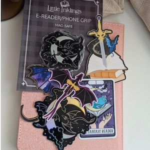 Moon and Dragons Acrylic Kindle Grip. A collection of fantasy-themed stickers and a Mag-Safe e-reader or phone grip on a pink textured surface.