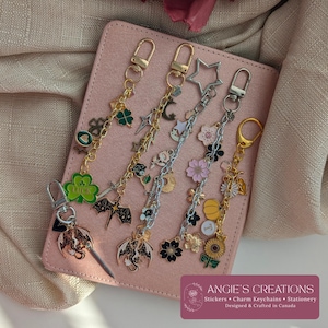 Pu&ograve; includere: Cinque portachiavi con ciondoli in metallo con vari design, tra cui un quadrifoglio verde con la parola LUCK, un drago nero, una stella argentata, fiori di ciliegio rosa, una zucca gialla e un girasole, fissati a moschettoni dorati e argentati.