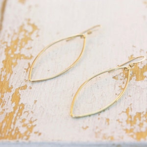 May include: A pair of gold leaf-shaped earrings with a simple, minimalist design.