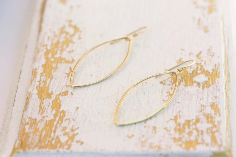 May include: A pair of gold leaf-shaped earrings with a simple, minimalist design.
