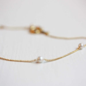 May include: A delicate gold chain bracelet with four small white pearls.