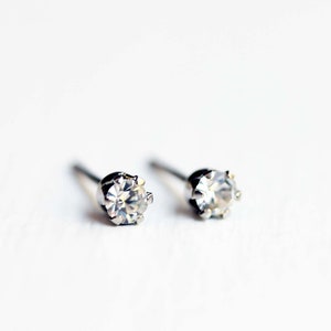 May include: A pair of silver stud earrings with clear round cubic zirconia stones.