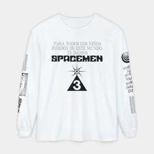 Könnte beinhalten: Weißes Langarmshirt mit dem Text "PARA TODOS LOS NIÑOS JODIDOS DE ESTE MUNDO, TE DAMOS SPACEMEN" und einer Grafik eines Sternenstrahls und der Zahl 3. Zusätzlicher Text und Grafiken auf den Ärmeln.