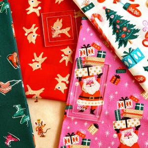 May include: Four different fabric swatches with a Christmas theme. The top left swatch is red with a white reindeer pattern. The top right swatch is white with a green Christmas tree and red and white candy cane pattern. The bottom left swatch is green with a white ice skate pattern. The bottom right swatch is pink with a gold and red present pattern and a Santa Claus figure.