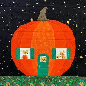 Peut inclure: Une citrouille en patchwork sur un fond noir avec des étoiles. La citrouille a trois fenêtres avec des souris qui regardent à l'extérieur de chacune d'elles. La citrouille est orange et a une porte verte.