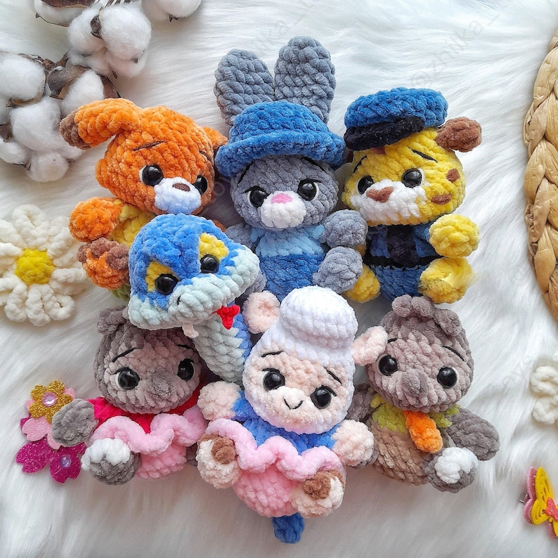 Op de afbeelding: Een verzameling handgemaakte gehaakte dierenknuffels. De collectie bevat een hond, een konijn, een tijger, een slang, een beer en een muis, elk gemaakt van zacht, kleurrijk garen. De knuffels hebben gedetailleerde gezichtskenmerken.