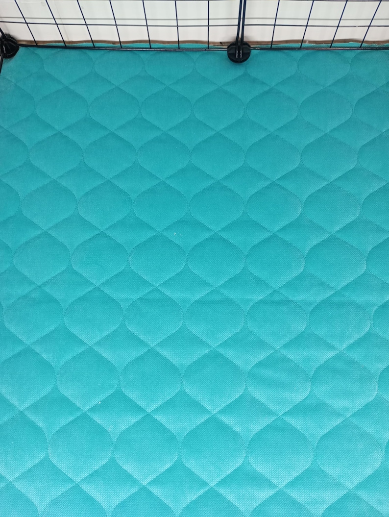 May include: A turquoise blue quilted cage liner with a diamond pattern. The liner is made of a soft, durable material and is designed to protect the bottom of the cage from dirt and debris.