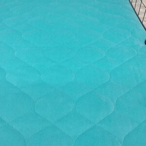 May include: A turquoise blue quilted cage liner with a diamond pattern. The liner is made of a soft, durable material and is designed to protect the bottom of the cage from scratches and dirt.