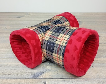 May include: A red and black plaid pet tunnel with red velvet lining and heart-shaped cutouts. The tunnel is made of two connected sections.