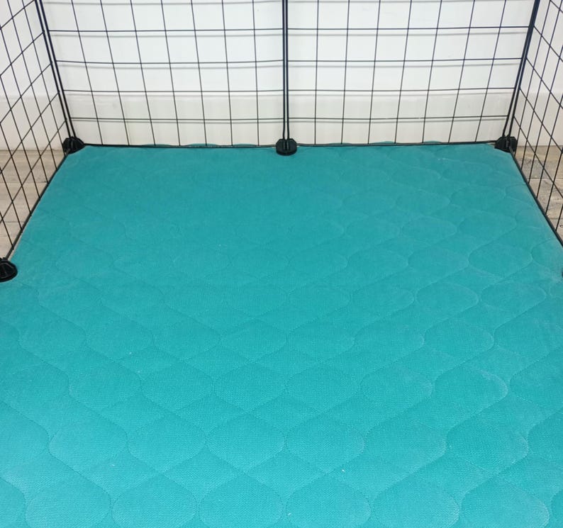 May include: Teal quilted pet bed liner for a large cage. The liner is made of a soft, durable material and is designed to protect the cage floor from scratches and dirt.