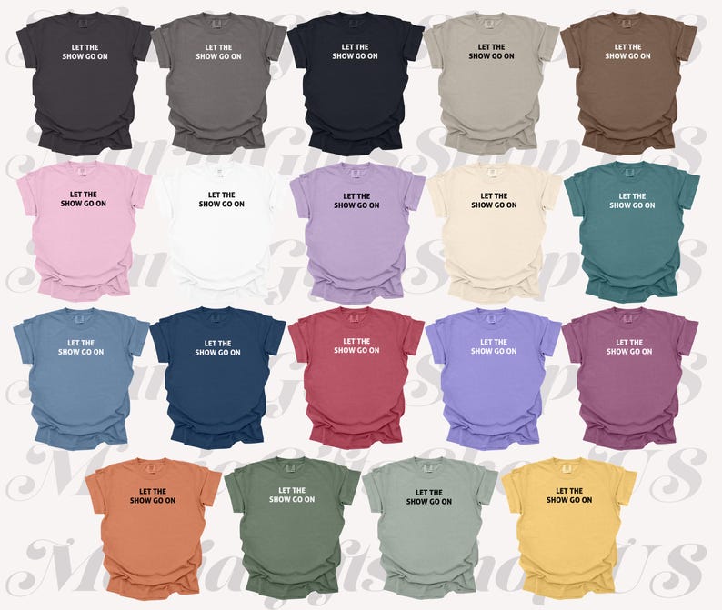 May include: A collection of short-sleeved t-shirts in various colors, each displaying the text "LET THE SHOW GO ON" in a simple, white font. The shirts are arranged in rows, showcasing a range of hues from dark to light.