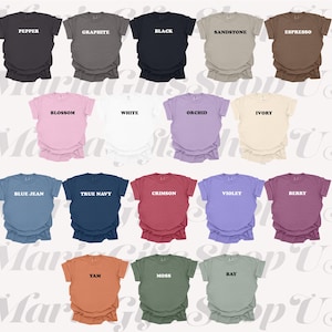 May include: A collection of short-sleeved t-shirts in various colors, including black, white, and blue. Each shirt has a different color name printed on the front. The shirts are neatly arranged, showcasing a range of hues.