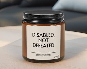 May include: A brown candle jar with a black lid. The label displays the text "DISABLED, NOT DEFEATED" in black. Below, it reads "NON-TOXIC | VEGAN | ECO-FRIENDLY HANDCRAFTED | NATURAL SOY WAX".