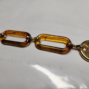 May include: A gold and brown chain with oval-shaped links. The chain has a gold clasp at one end.