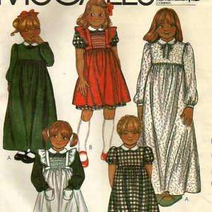May include: Illustration of five vintage children's dresses. The dresses are in various styles and colors, including green, red, and floral patterns. Each dress features a different design, such as smocking, plaid, and ruffled details. The image is a pattern for sewing.