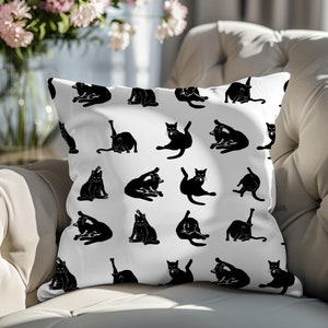 May include: White throw pillow with a black and white repeating pattern of cats in various poses.