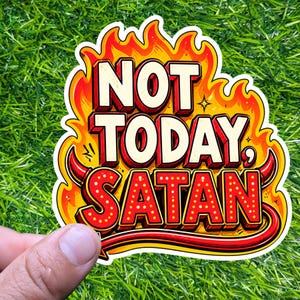 May include: A sticker with the text "NOT TODAY, SATAN" in a bold, retro font. The words are outlined in red and white, with a flame design in orange and yellow. The sticker has a devil horn design.